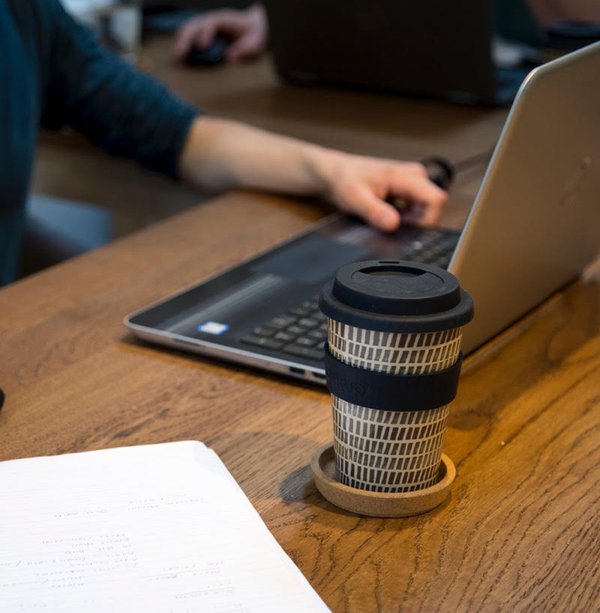 Person using Bear & Bear reusable coffee mug while sat at a desk