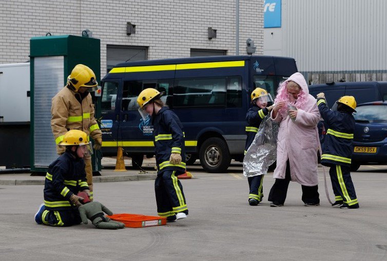 A photo of two young fire cadets receiving wisdom from a firefighter