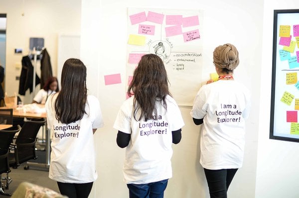 Three young competitors in the Longitude Explorer Prize brainstorming and placing post-it notes on the wall