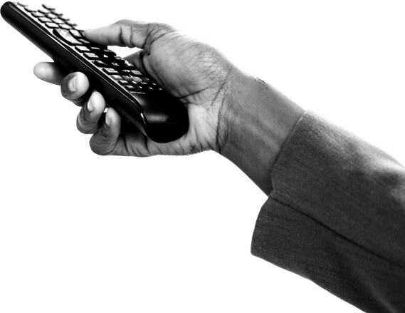 A person's hand holds a remote control, with fingers positioned on the buttons.