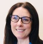 Headshot of a smiling woman with dark hair and glasses, possibly a staff member or featured individual.