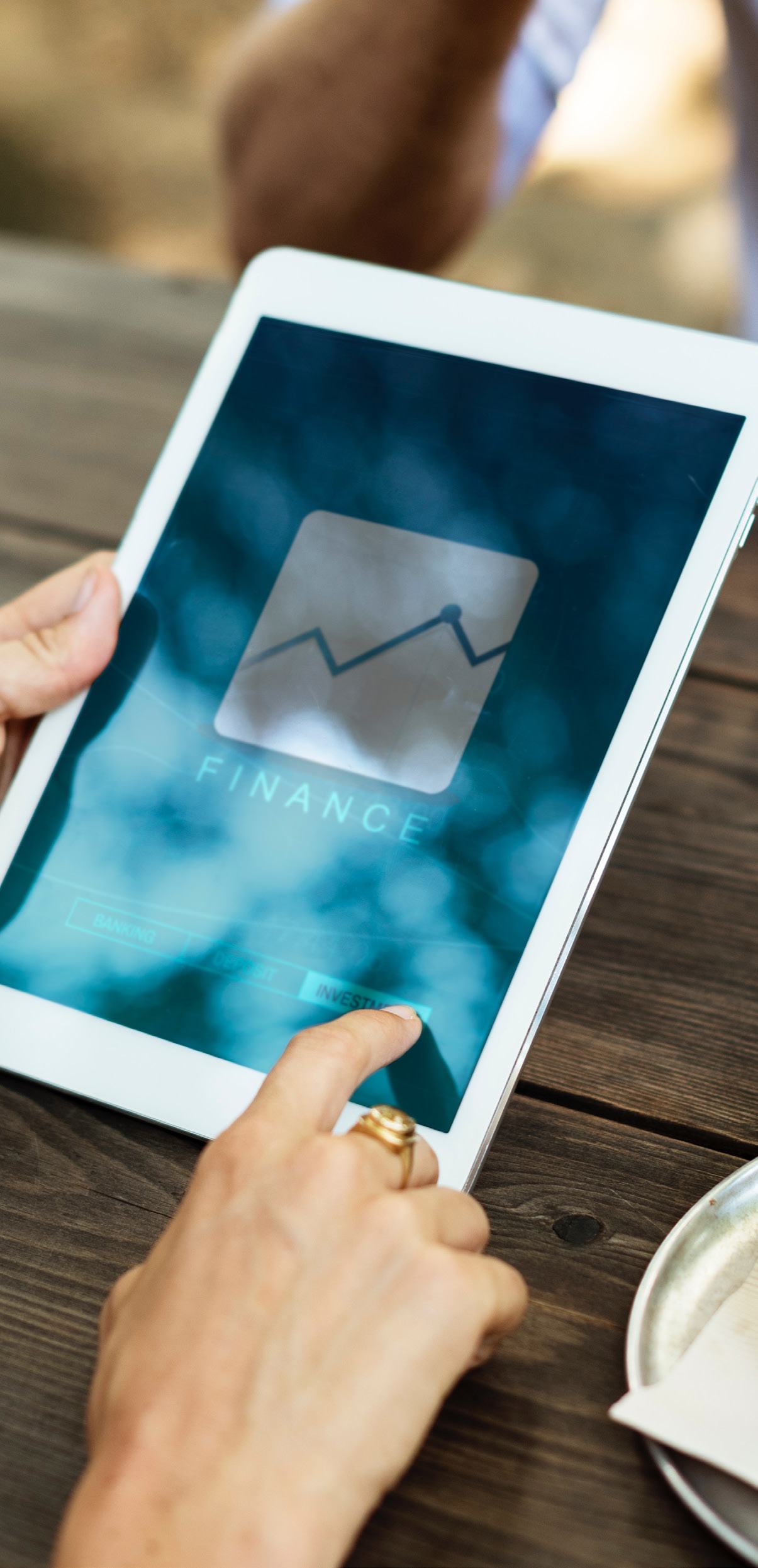 Hands holding a tablet displaying a finance application with a graph icon and "FINANCE" text.