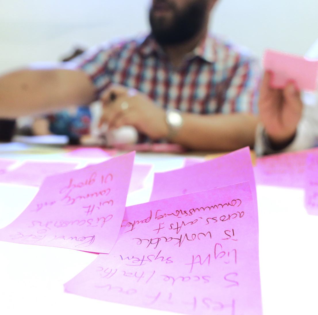 Close-up of multiple pink sticky notes on a table with handwritten project ideas and concepts.