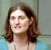 Headshot of a woman with brown hair, wearing a teal top and a lanyard.