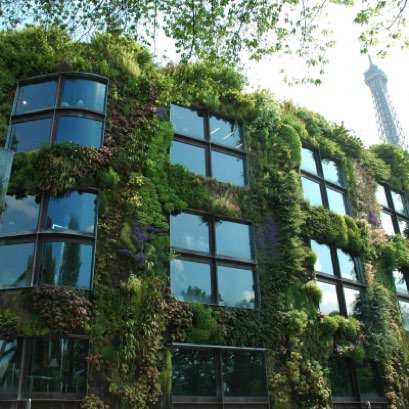 Building with a lush green vertical garden covering its exterior walls and large windows. The Eiffel Tower is visible in the background.