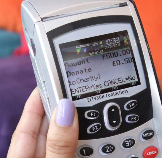Close-up of a payment terminal screen showing a prompt to donate £0.50 to charity from a £500.00 transaction.