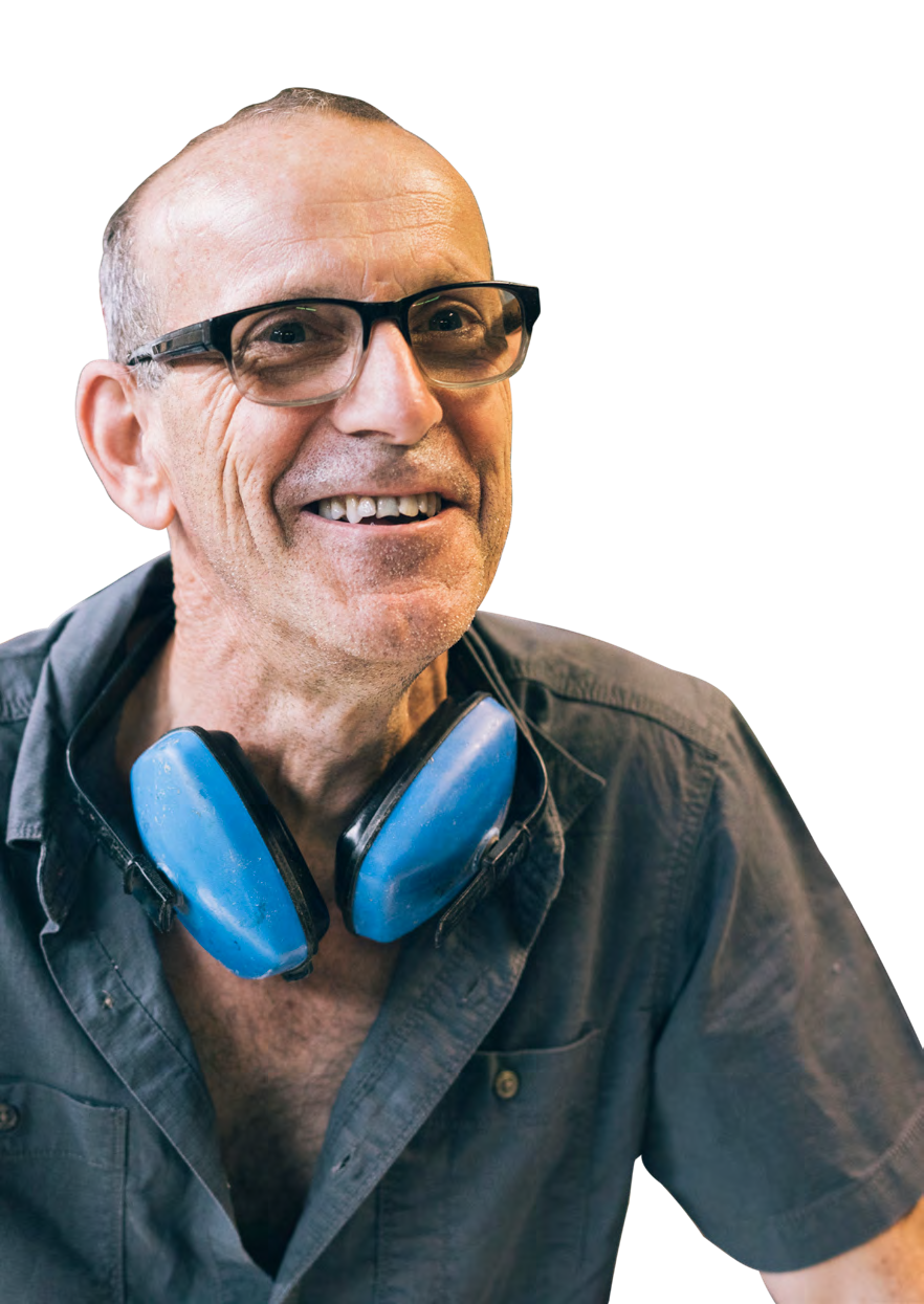 Portrait of a smiling man with glasses, wearing blue ear protection around his neck.