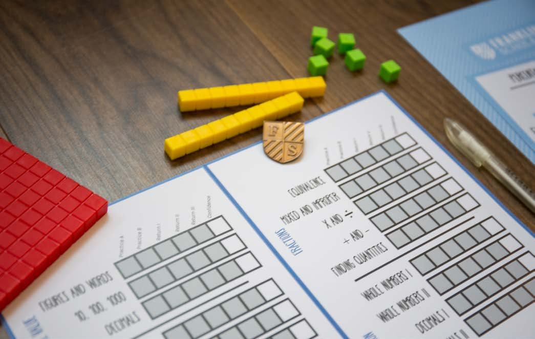 Educational materials, including a math worksheet with grids for fractions and whole numbers, alongside colored math manipulatives.