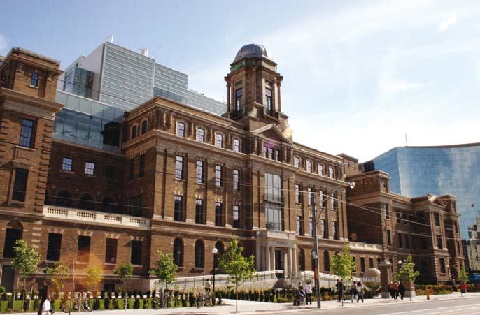 Exterior view of a historic brick building with modern glass additions on a sunny day.