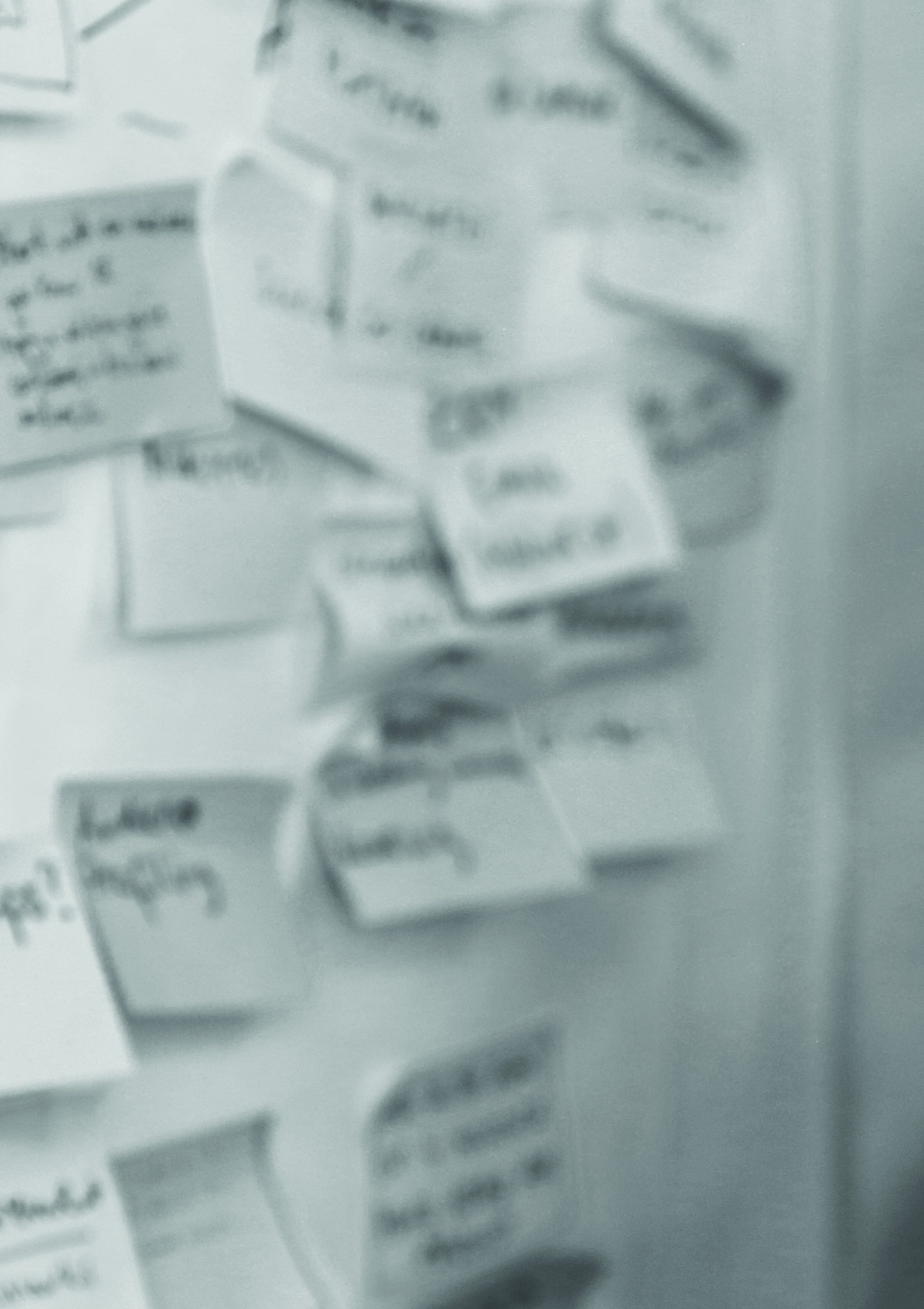 Blurred close-up of a wall covered with numerous sticky notes, representing a brainstorming session or affinity diagram.