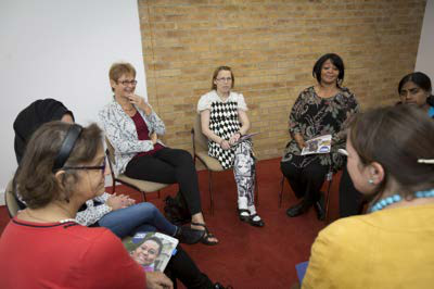 Diverse group of women sitting in a circle, engaged in a discussion or support group meeting.