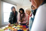 Group of women of different ages engaging with colorful art projects on a table.