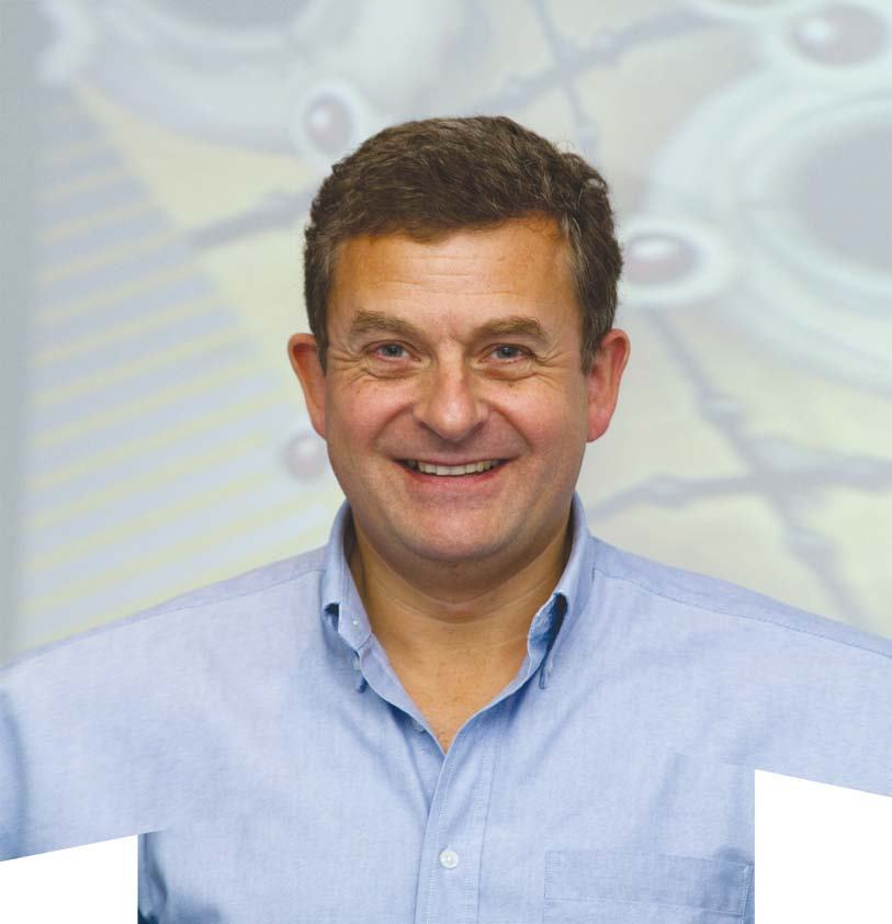 Portrait of a smiling man in a light blue collared shirt.