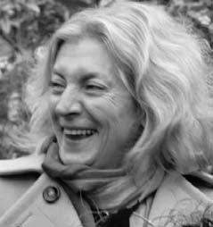 Black and white headshot of an older woman with curly hair smiling, wearing a coat and scarf.