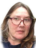 Headshot of a woman with long brown hair and glasses, wearing a blue top.