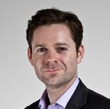 Headshot of a smiling man with short dark hair, wearing a dark suit jacket and purple shirt.