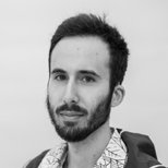 Headshot of a man with a beard and short dark hair, wearing a patterned shirt.
