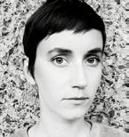 Headshot of a woman with short dark hair, looking directly at the camera, against a textured background.