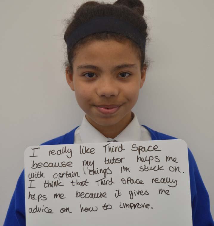 A young girl holding a handwritten sign with a testimonial about her tutor helping her with Third Space.
