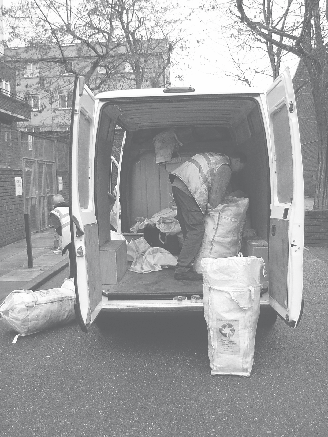 Worker in a high-vis vest loads recycling bags into the back of a white van, with more bags on the ground, illustrating waste collection.