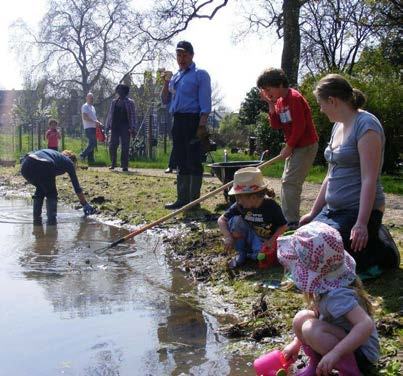 Adults and children exploring a pond during an outdoor learning or community activity.