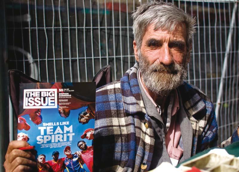 A bearded man holds up a copy of "The Big Issue" magazine, featuring "Smells like Team Spirit" on the cover.