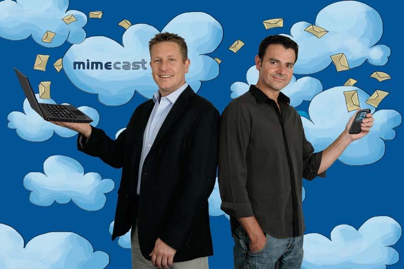Two Mimecast employees holding a laptop and smartphone against a cloud background with flying envelopes, representing cloud-based email services.