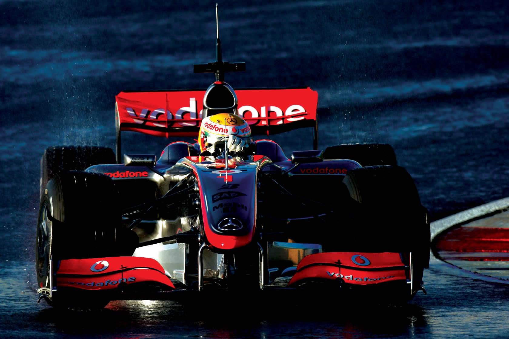 A Vodafone McLaren Mercedes Formula 1 race car on a wet track, viewed from the front, showcasing branding and design.