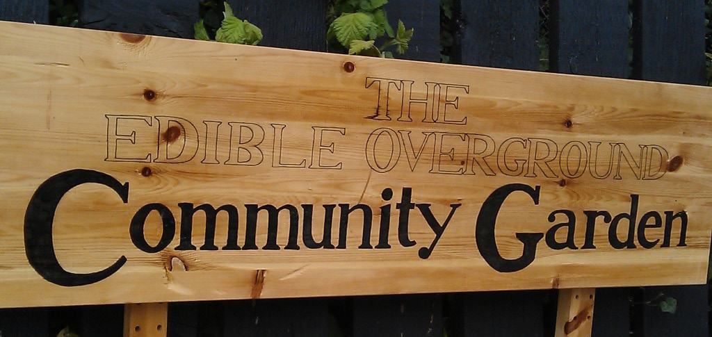 A wooden sign for "THE EDIBLE OVERGROUND Community Garden".