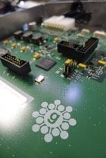 Close-up of a green circuit board with electronic components and a white logo featuring a 'g' surrounded by circles.