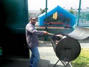 A man grilling food on a barbecue outdoors, with a blue bouncy castle in the background.