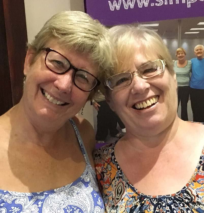Two smiling women with short hair and glasses, looking directly at the camera.