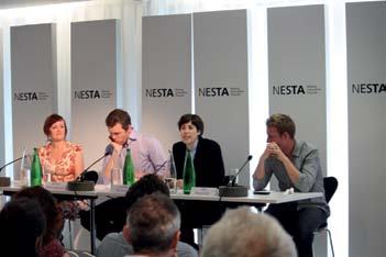 Panel discussion with four speakers seated at a table, addressing an audience in a room with "NESTA" logos on background panels.