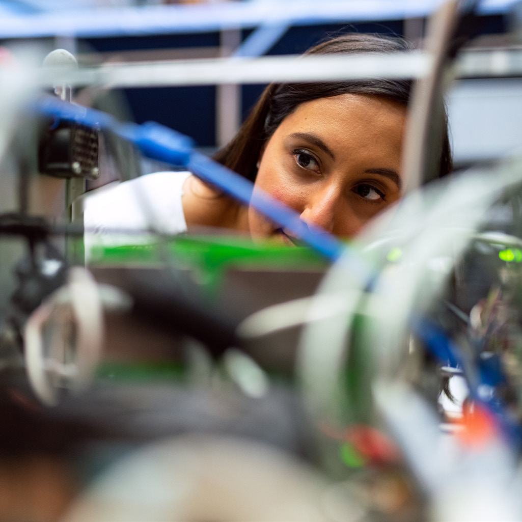 A person intently examining complex technical equipment with visible wires and circuitry.