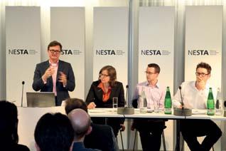 Panel discussion at a NESTA event, with a speaker standing at a podium and four panelists seated at a table.
