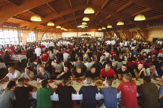 A vast hall filled with many people seated at long tables, attending a large indoor event or dinner.