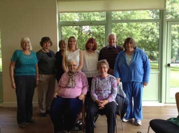 Group photo of ten older adults, mostly women, smiling at the camera in an indoor setting.