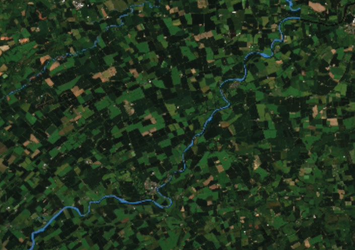 Satellite view of a rural landscape with agricultural fields and a winding blue river.