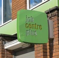 Green sign for 'job centre plus' attached to a brick building.