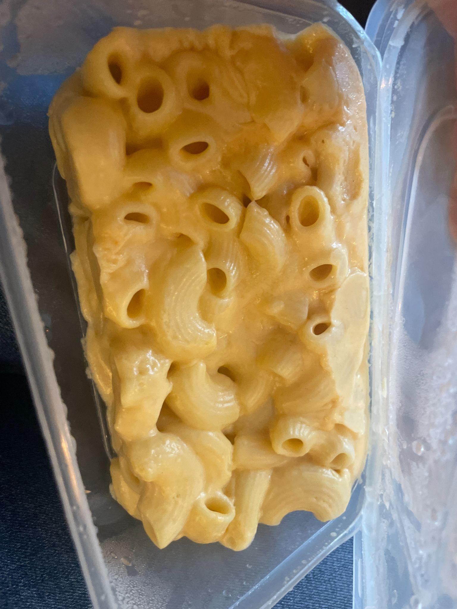 Macaroni cheese in a clear plastic container, seen from above.