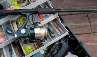 Fishing rod and reel resting on an open tackle box filled with lures and fishing gear.