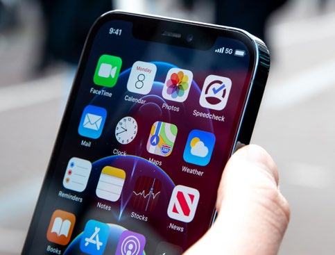 Close-up of a hand holding an iPhone displaying a screen with various app icons, including FaceTime, Calendar, Photos, and Maps.