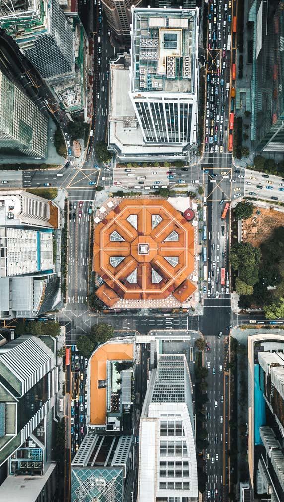 High aerial view of a dense city intersection with traffic, surrounded by tall buildings, centering on a distinctive octagonal building.