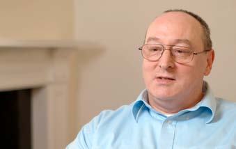 Portrait of a middle-aged man with glasses and a blue shirt, looking thoughtfully.