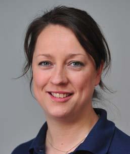 Close-up portrait of a smiling woman with dark hair and a dark blue collared shirt.