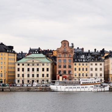 Waterfront view of a European city with colorful historic buildings and a large white boat docked along the river.