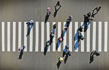 Aerial view of people walking across a white-striped pedestrian crosswalk.