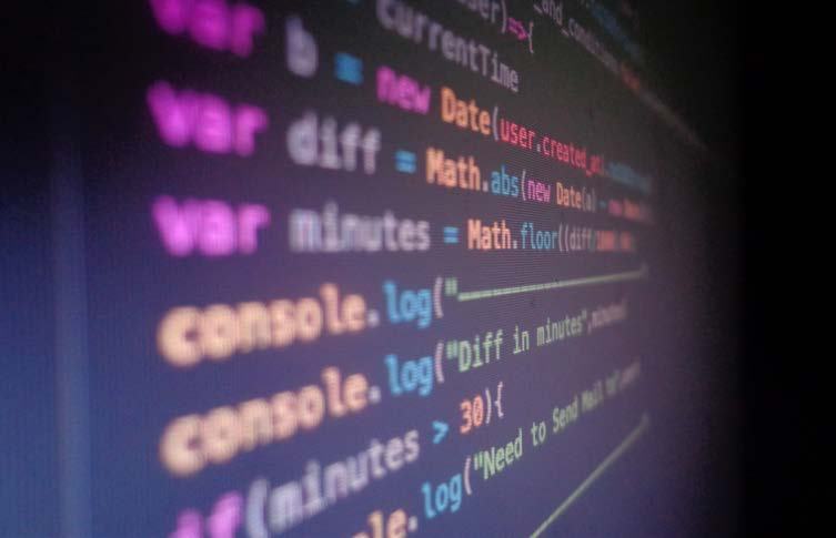 Close-up of a computer screen displaying JavaScript code with variables, functions, and console logs in a dark theme.