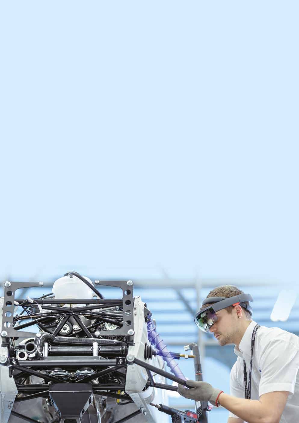 Worker wearing an augmented reality headset inspecting complex machinery in an industrial setting.