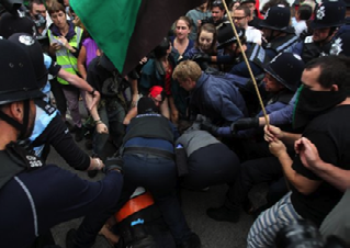 Police officers and protesters clashing in a street, indicating a moment of intense confrontation during a demonstration.